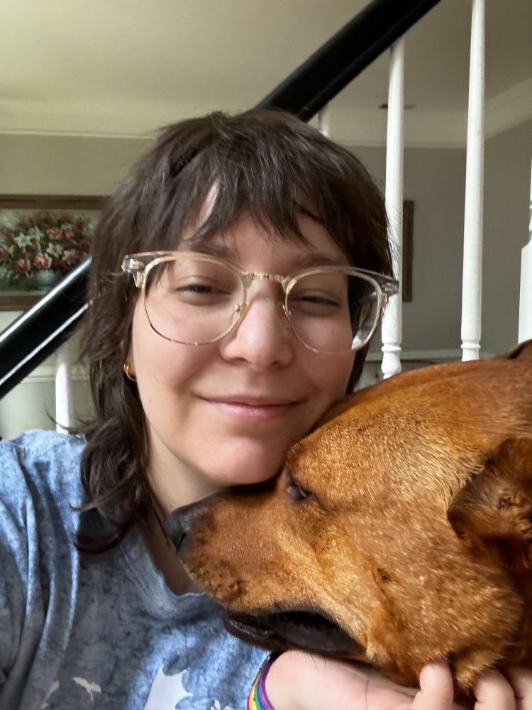 A selfie of me with my sister’s dog Haizel. She’s a mixed breed with copper fur. I’m smiling without teeth while holding her head with my chin resting on top of her snoot.