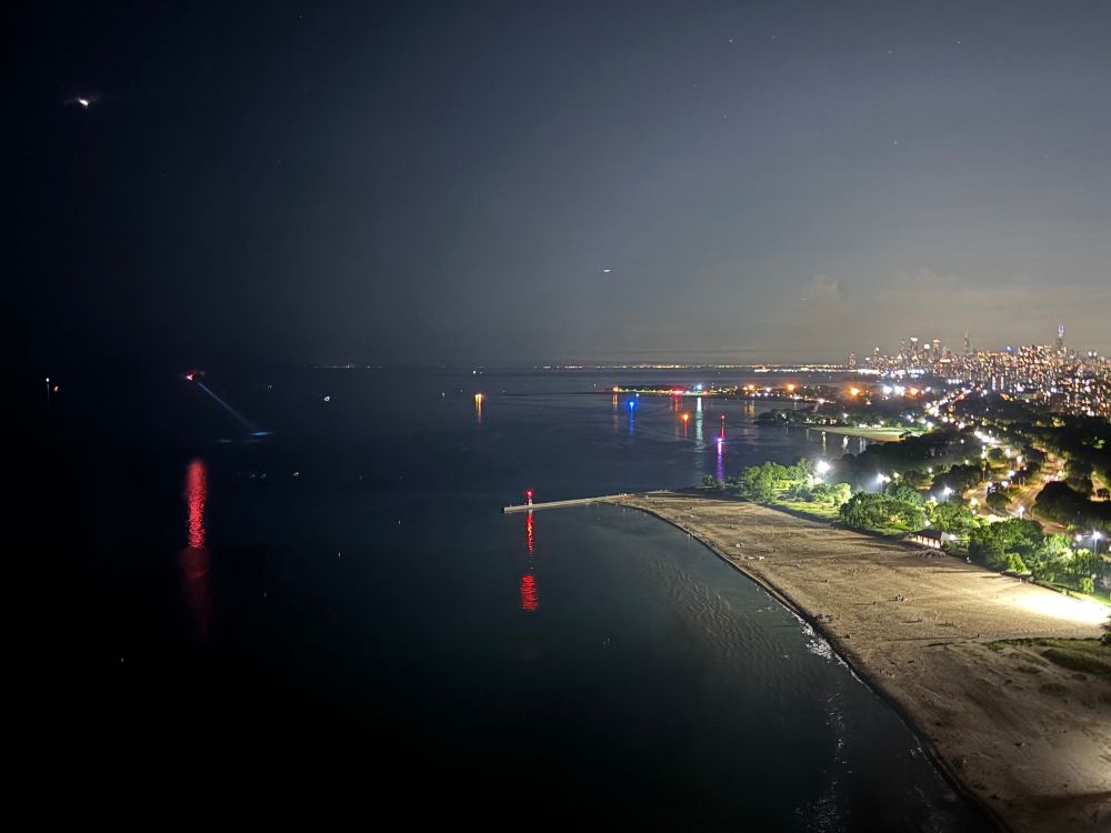 The Chicago waterfront at night. The lights from a police helicopter and boats are visible in the distance.