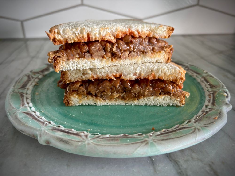 A sandwich with baked beans on a blue plate