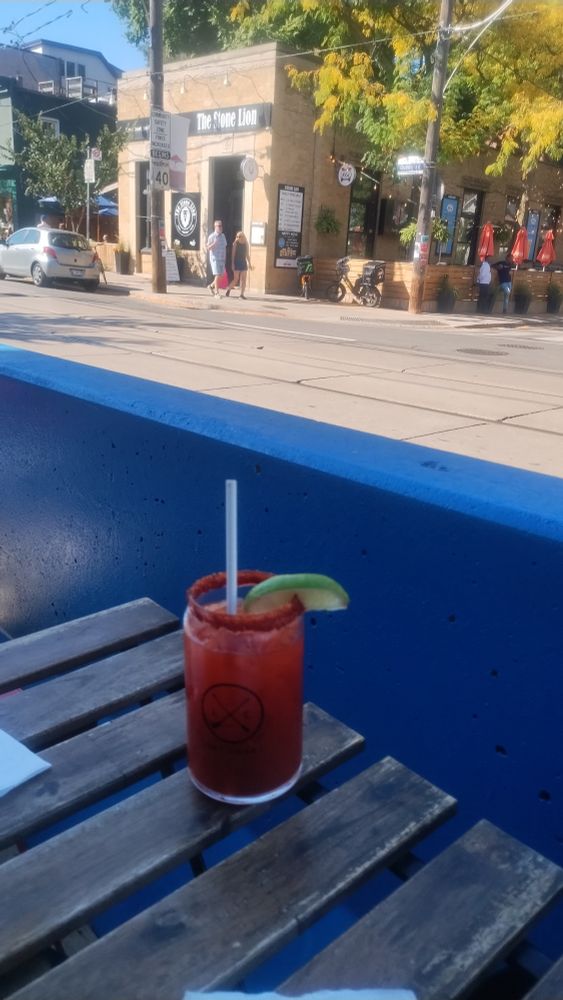 Cesser with tajin rim and lime on patio table. Blue roadblock and city street in background.