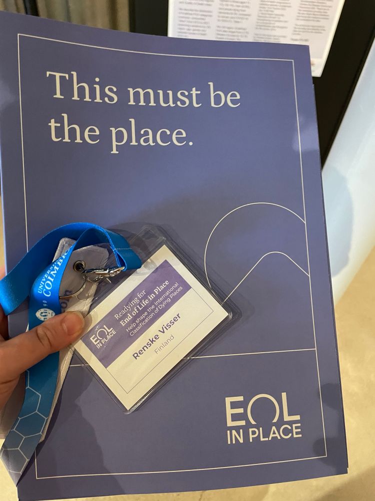 Hand holding Purple folder with the text “This Must Be the place “ and a lanyard with my name on it 