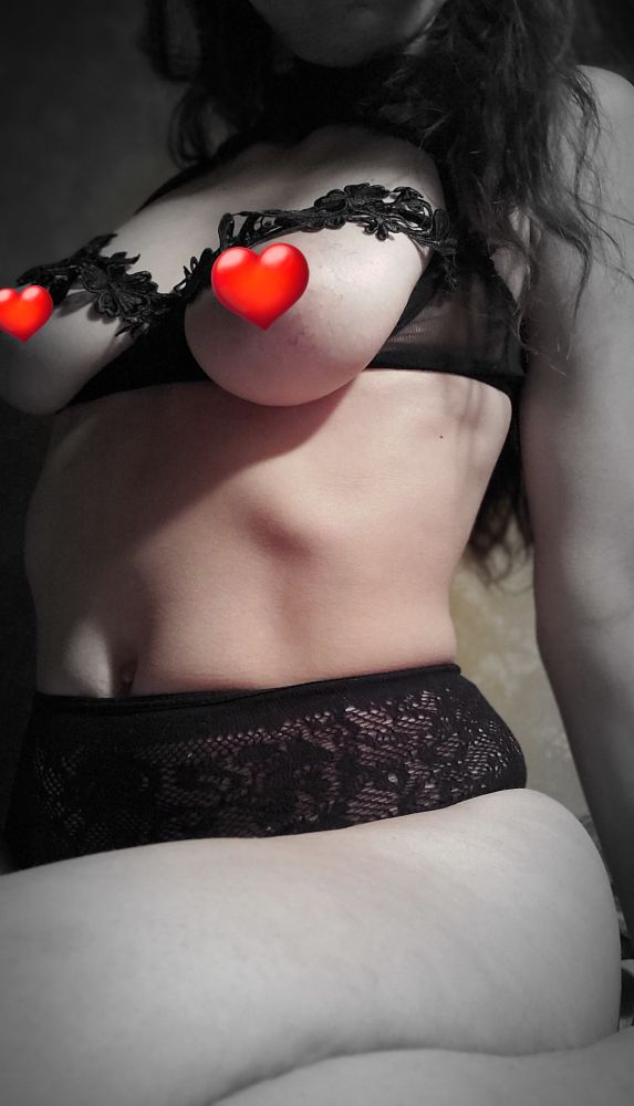 a close up photo of sal in black floral lace. chest is visible. censored with red heart stickers.
