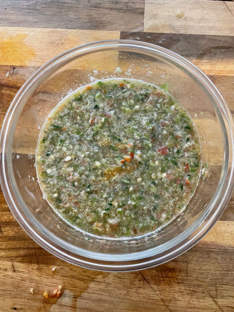 Green salsa in a glass bowl on a wooden cutting board. It was SPICY and perfect 