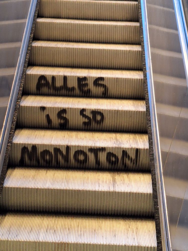 Rolltreppe mit Graffiti "ALLES IS SO MONOTON"