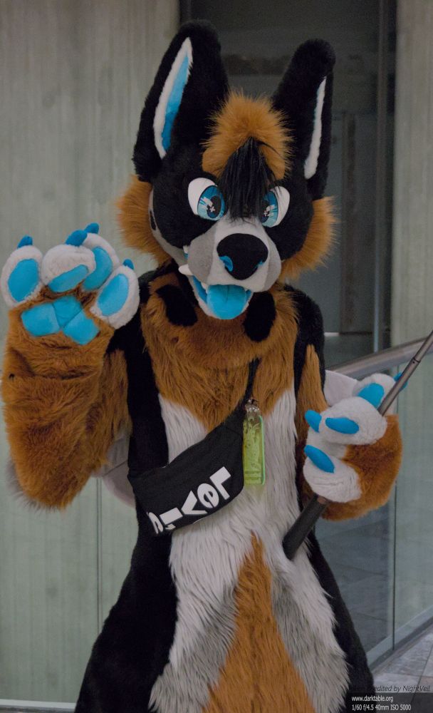 Eubean (full suit) holding a selfie stick and waving to the camera