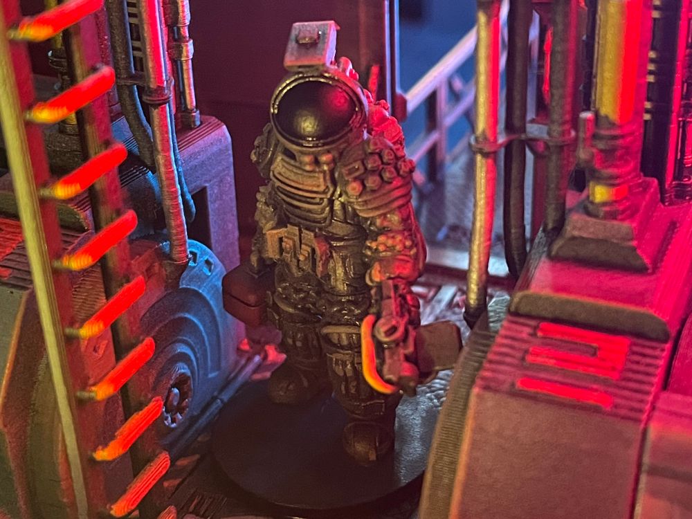 Photograph of a 28mm scale space man inside a model space ship with some atmospheric lighting.