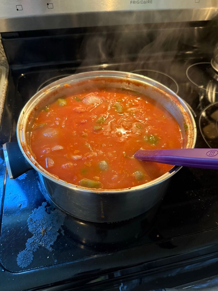 A large pot of tomato sauce gently cooking on a stove