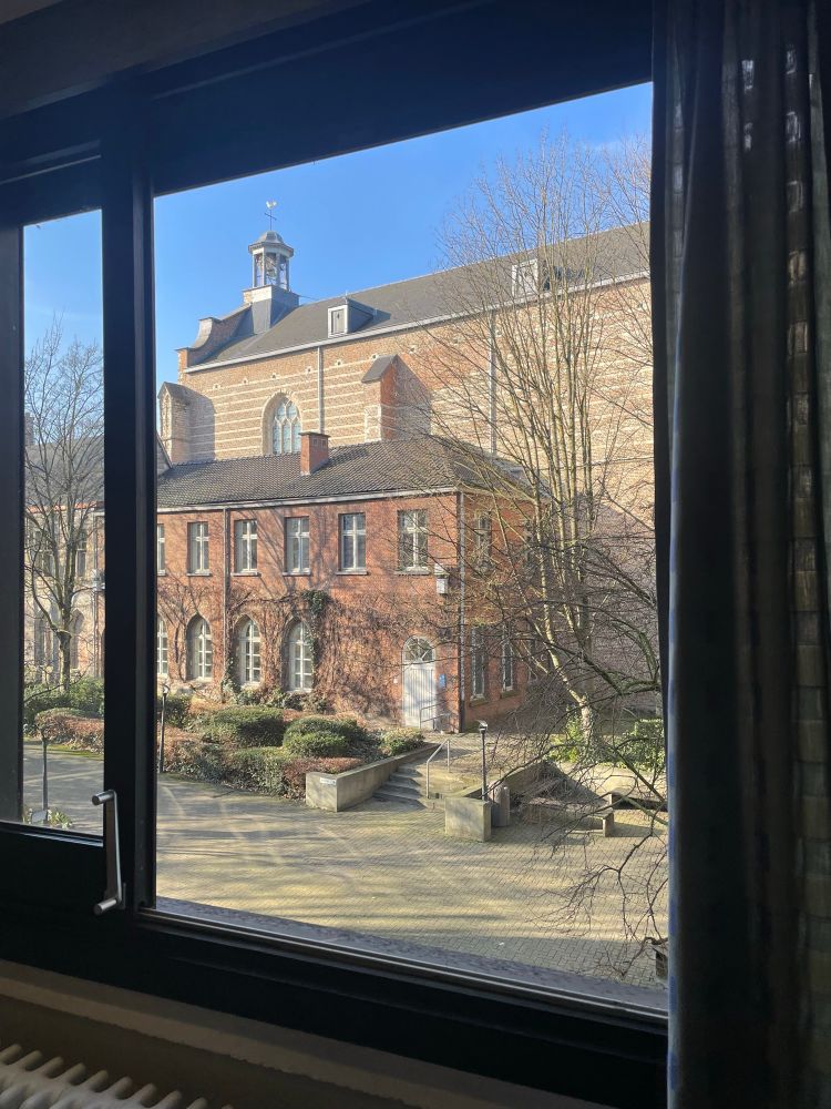 View of an old red brick church and blue skies from an open window