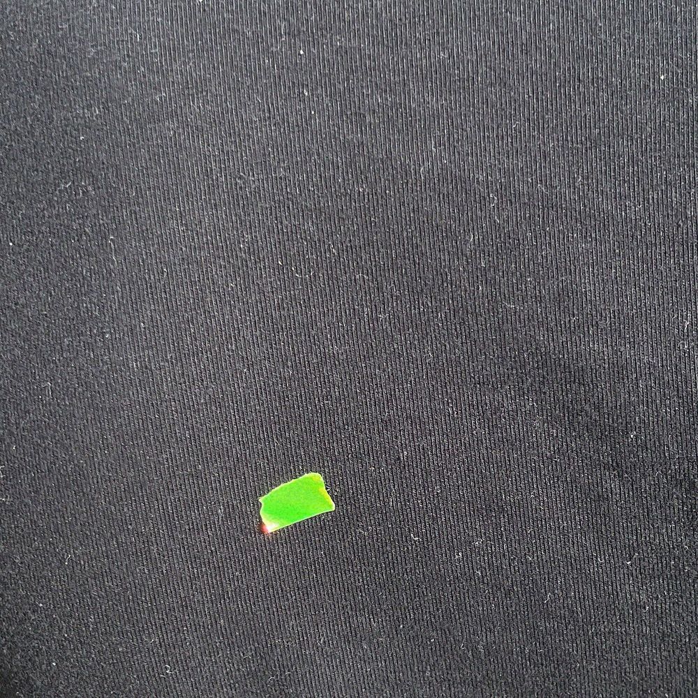 Die Artwork des Songs Gratis. Ein schwarzes T-Shirt auf dem sich ein kurzes Stück eines flureszierend neon-grünem Streifen Tape befindet, welches sich leicht in der Sonne spiegelt.