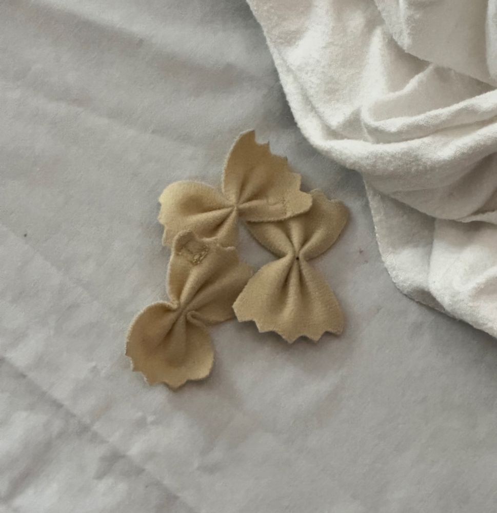 3 fabric bow tie pastas sitting on a napping mat