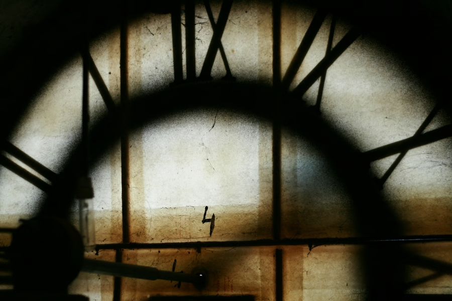 A slightly unsettling shadow of a large clockface looming over a grungy backdrop.