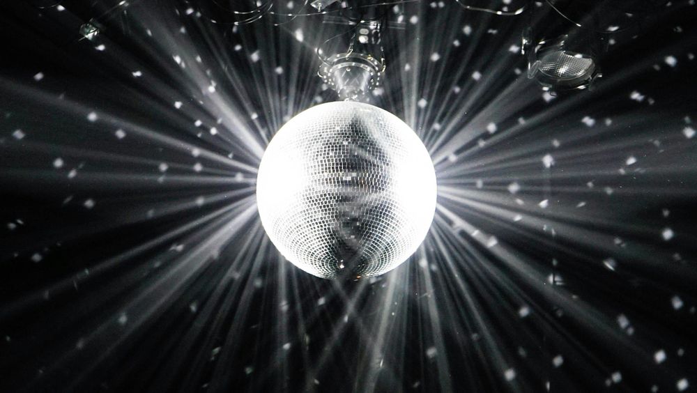 A black and white photo of a disco ball reflecting light from all sides.