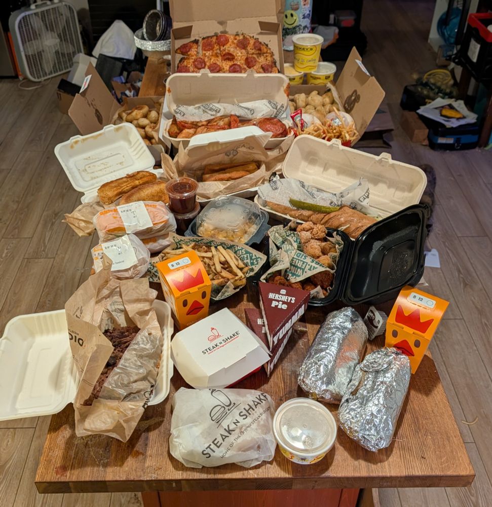 A butcher block covered in fast food. Steak 'n Shake, Domino's Pizza, Wingstop, Dickey's barbecue, Burger King, Chipotle, Firehouse Subs.