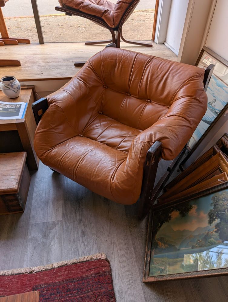 Orange Leather Percival Lafer MP-97 lounge chair sitting by a sunny window in an antique shop.