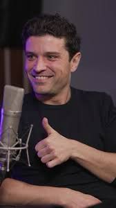 Miguel Maldonado en un podcast, sonríe de manera cómplice y levanta el pulgar en aprobación 