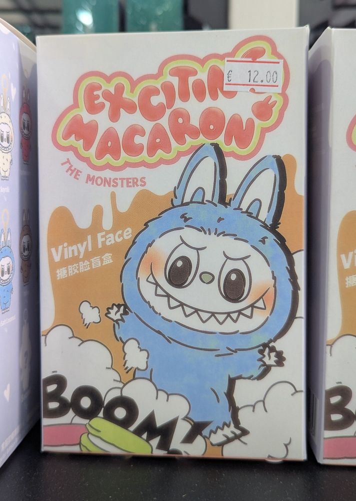 Eine Packung mit einem gefälschten Labubu, dieses heißt "Exiting Macaron", auf der Packung steht außerdem "The Monsters", "Vinyl Face" (auch auf Chinesisch) und "Boom!" 
