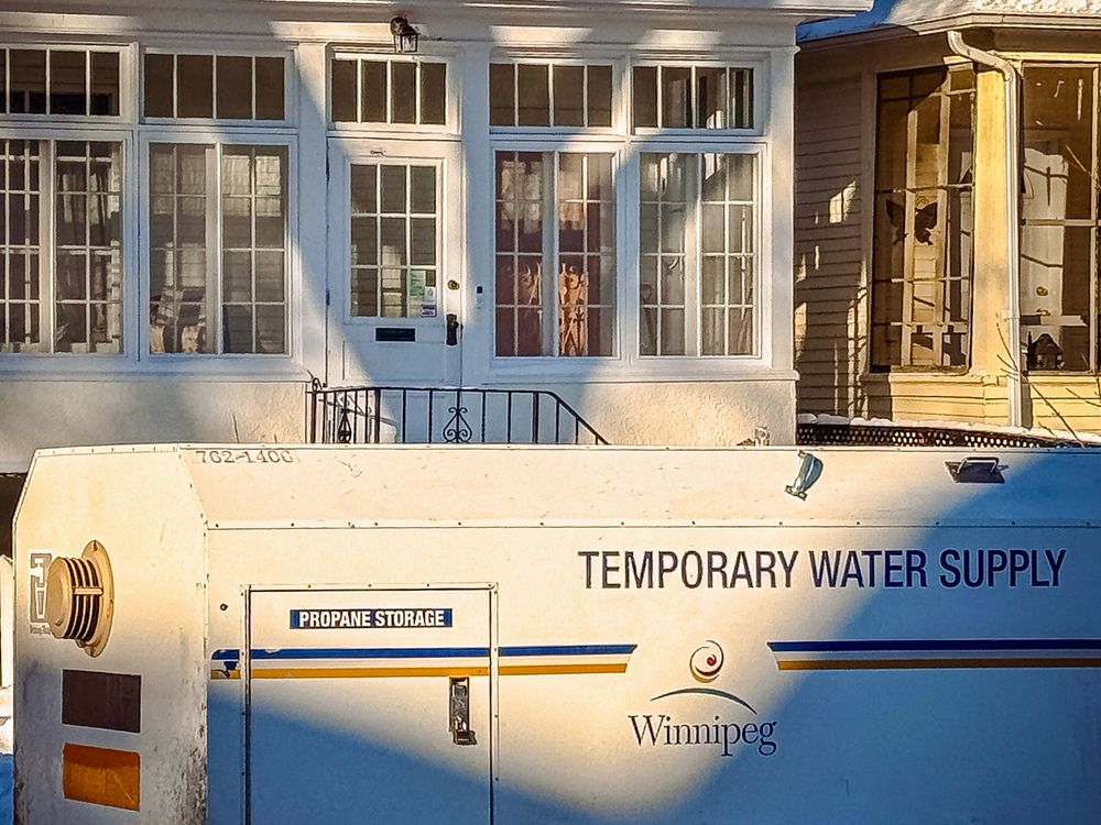 The sun rises to shine onto a City of Winnipeg temporary water supply tank, parked on a residential street. 