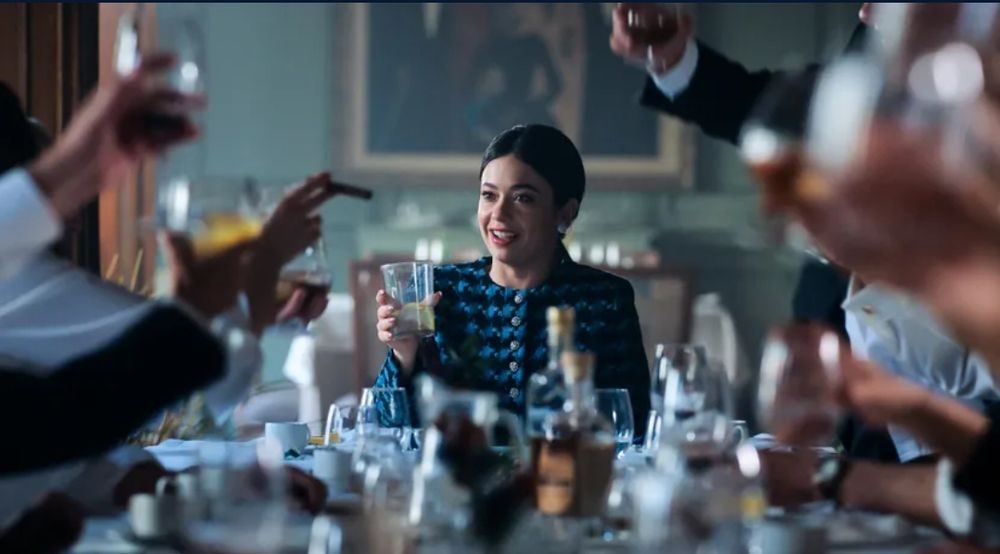 Fotograma de la serie "Su majestad" en el que la princesa (interpretada por Ana Castillo) sale en un restaurante brindando con jueces conservadores que se vanaglorian de haber metido en la cárcel a personas por ejercer su libertad de expresión.