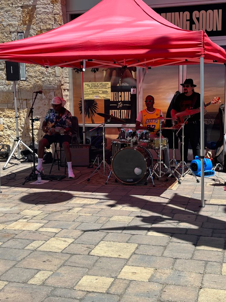 A three-person band playing under a canopy.