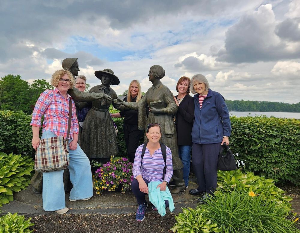 A group of six LDS women historians pose with statue of E.F. Stanton, A. Bloomer, and S. B. Anthony in Seneca Falls, NY. 