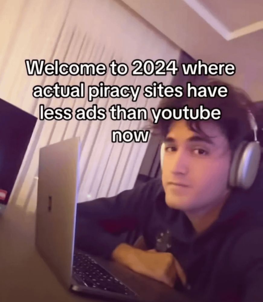 Image showcasing sad guy in headphones at a laptop. Caption reads “Welcome to 2024 where actual piracy sites have less ads than YouTube now”.