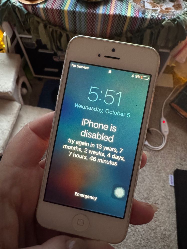 An old iPhone with a screen that reads “iPhone is disabled, try again in 13 years, 7 months, 2 weeks, 4 days, 7 hours, 47 minutes”