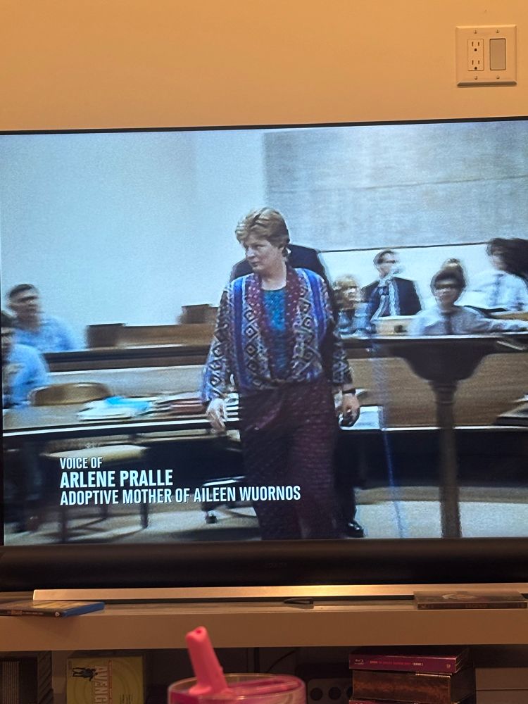 a picture of a TV showing a white woman in … some real 90s patterns and shapes. 