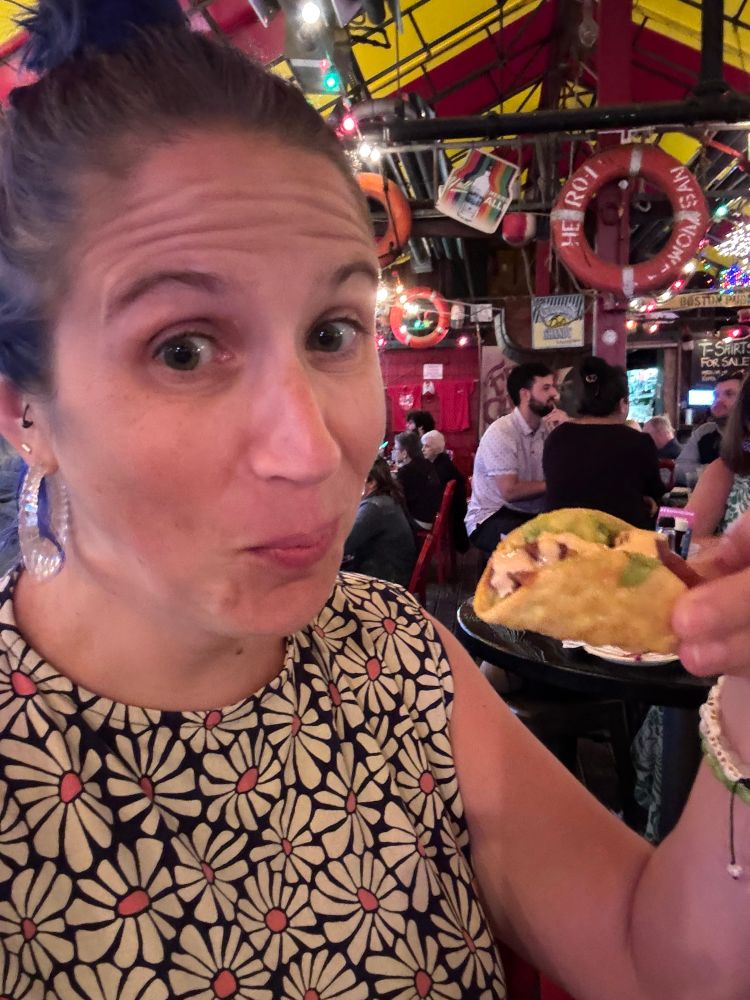 a white lady eating tiny taco - mouth closed