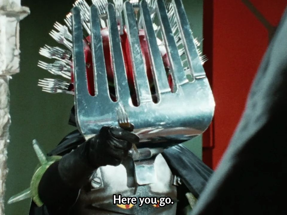 Fork Mask offers the fork plucked from his head to Daita as a dining utensil.