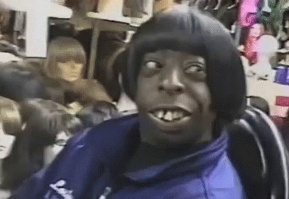 a man with a wig on his head is making a funny face while sitting in a chair in a store .