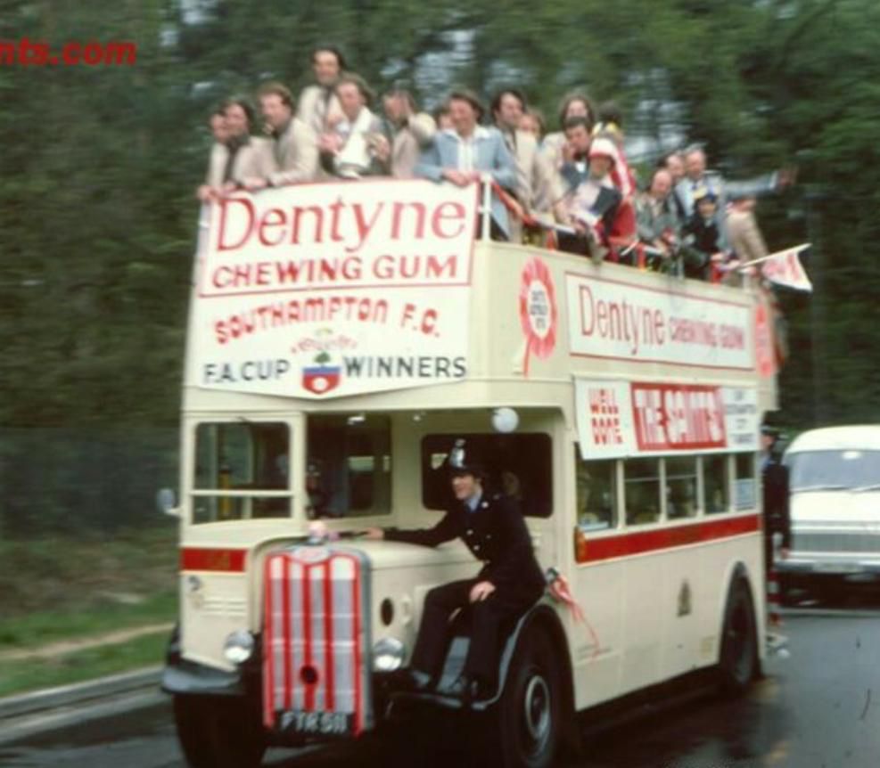 Cream coloured open top bus used by Saints in the 1976 cup win, bedecked in red and white with players on the top deck.