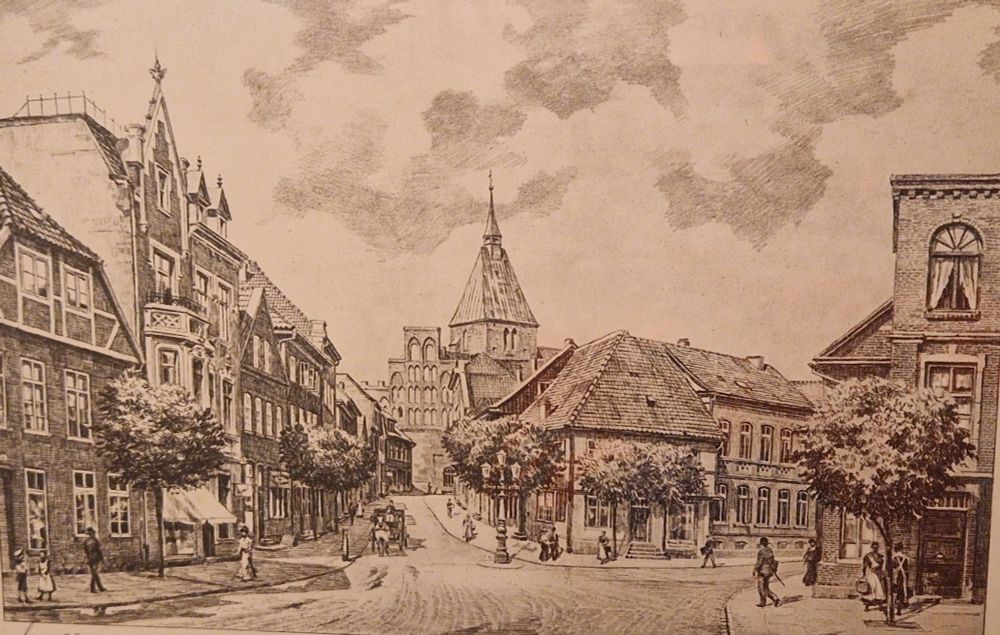 Sepiafarbene grafische Darstellung einer historischen Stadtansicht. Eine gepflasterte Straße führt zwischen mehrgeschossigen Fachwerk- und Backsteinhäusern hindurch auf eine Kirche mit Turm im Hintergrund zu. Auf der Straße sind mehrere Personen zu Fuß sowie eine Kutsche zu sehen. Bäume säumen den Platz. Am unteren Rand ist eine handschriftliche Signatur erkennbar.