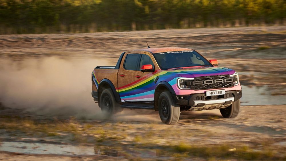 The very gay Ford Raptor pickup, which has a progressive pride rainbow painted across the front and is sparkly gold on the back 
