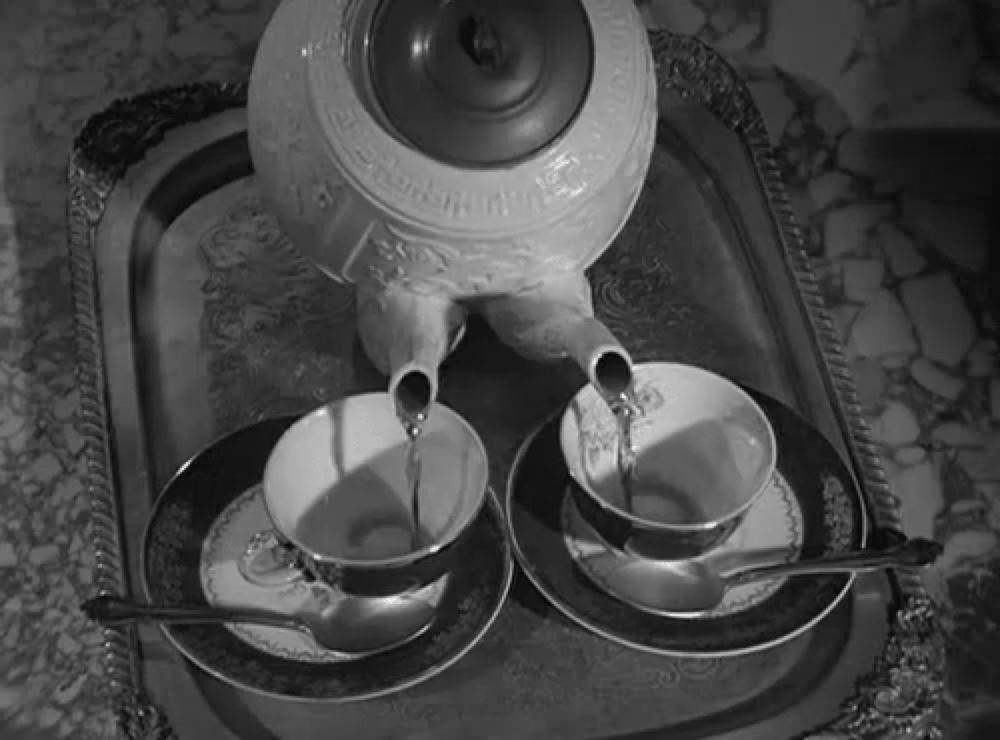 a black and white photo of a tea set with a teapot and two cups