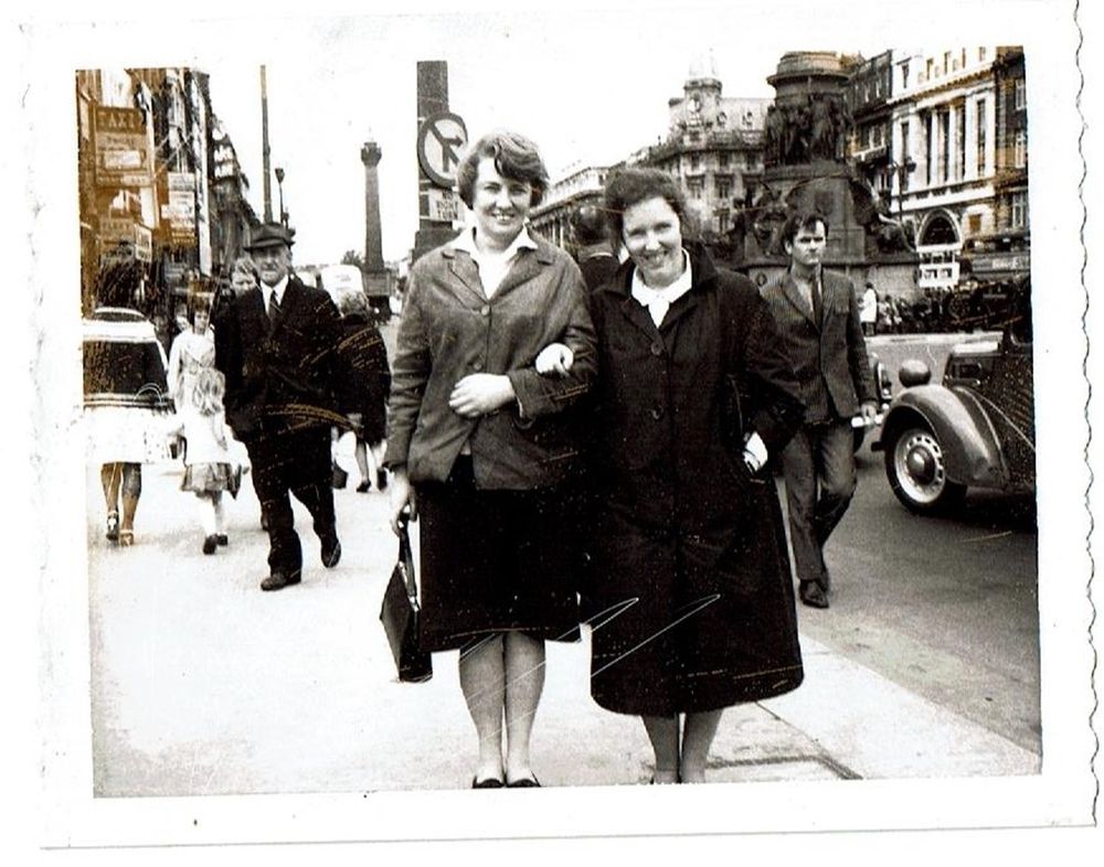 Two women on Dublin's O'Connell bridge arm in arm, black and white photograph