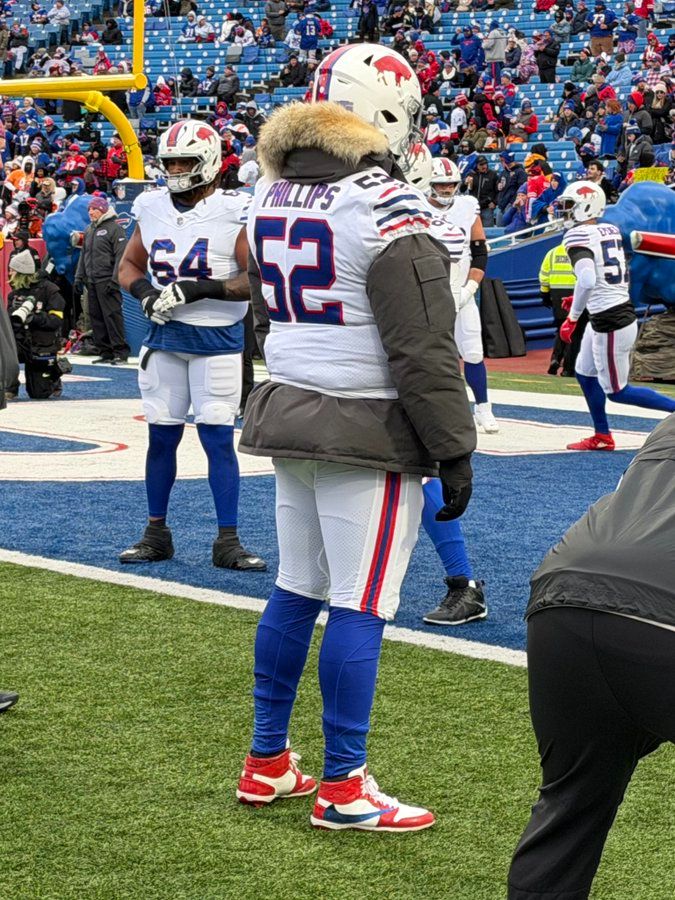 A pro footballer on the sidelines, wearing a parka under his jersey 