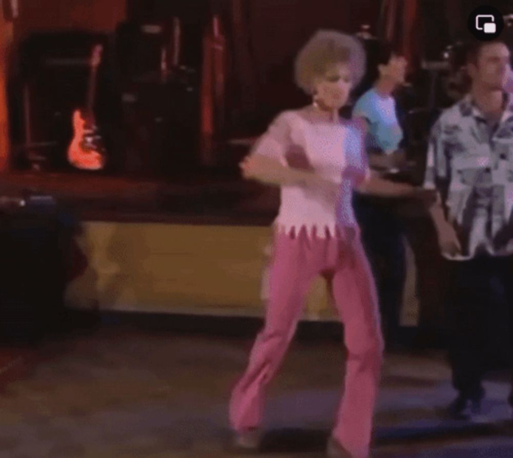 a woman in pink pants is dancing on a dance floor with other people .