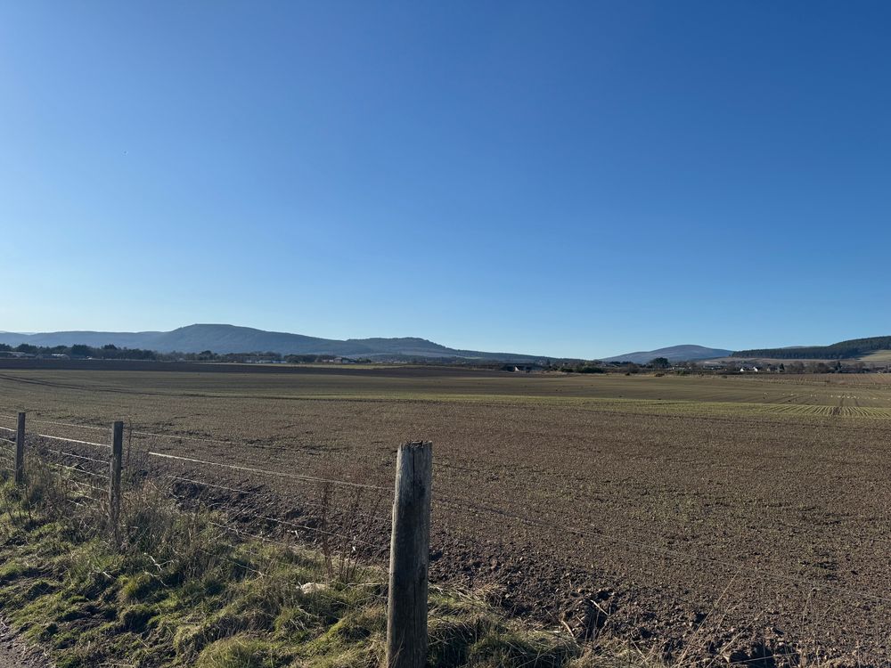 Clear blue sky over a ploughed field looking from Dalmore towards Fyrish Monument.