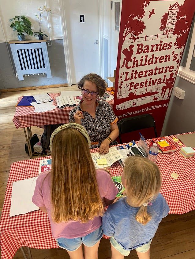 Me raising my fist as though I am going to punch a child but I look happy so probably that wasn't it. Two children with long hair are waiting for their signed books.