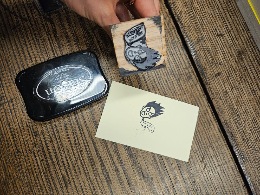 A stamp of my character loki's face saying foolish mortals and a test of the stamp on a post it, plus an ink pad. 
