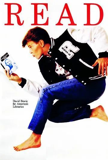 A poster shows David bowie leaping in the air reading a book. He's wearing jeans and a lettermans jacket saying ROOTS. The book looks like a penguin classic and shows a man with a beard but the resolution isn't good enough to tell exactly which book. The header says READ and the smaller text on the poster says David Bowie for America's Libraries.