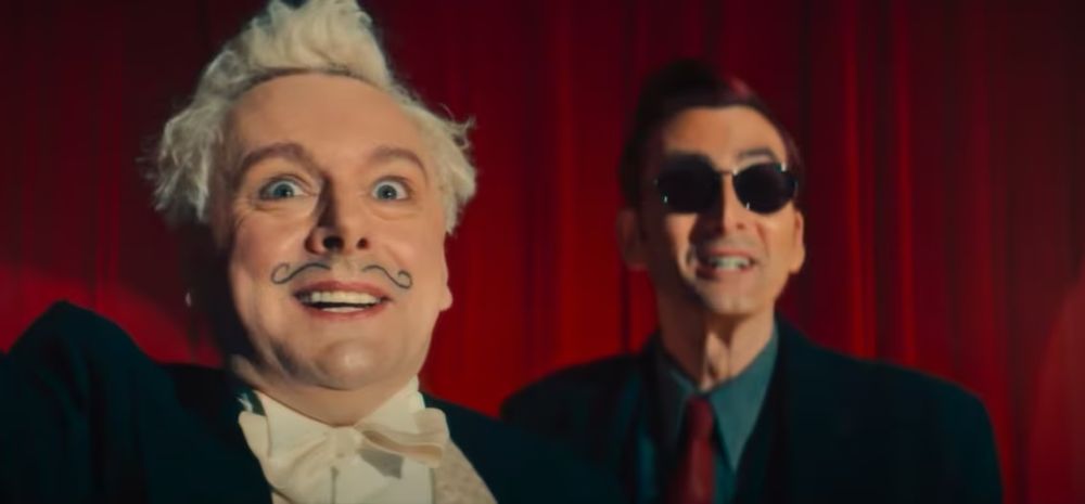 Season 2 Aziraphale looking ecstatic while wearing his magician costume. Crowley is behind him in his 1940s clothes.