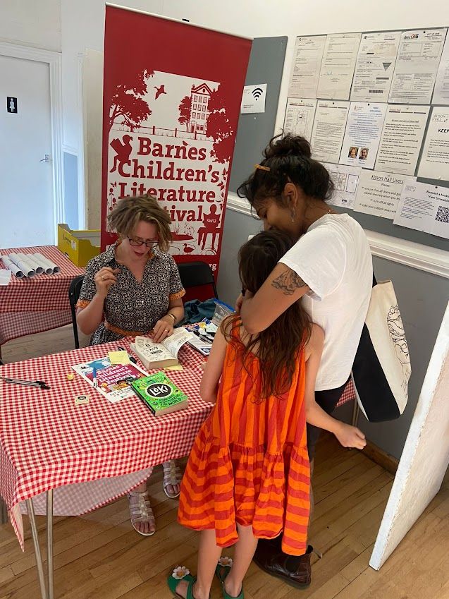 Girl and her adult hugging while I sign a book for her
