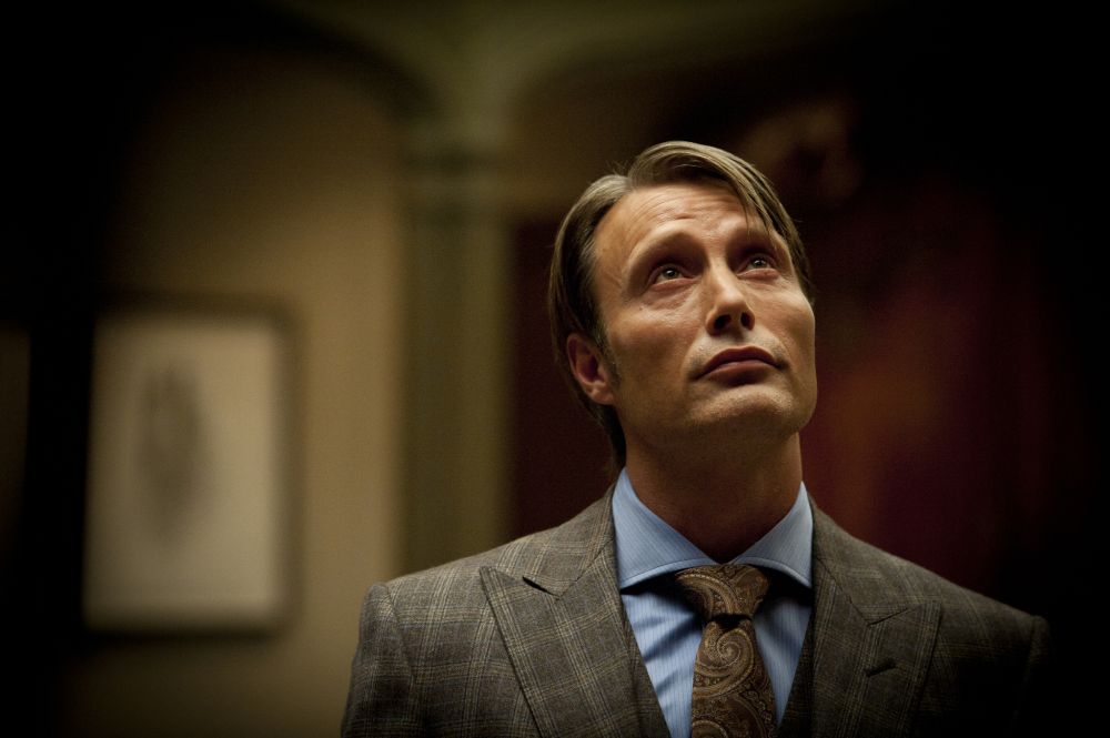 hannibal from the gay cannibal show. he's wearing a nice suit and looking up. Has he spotted someone he wants to eat up there? Perhaps will, on the balcony?