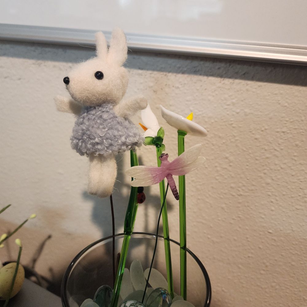 The same three glass stem flowers, with a little glass dragonfly and a small Easter bunny 