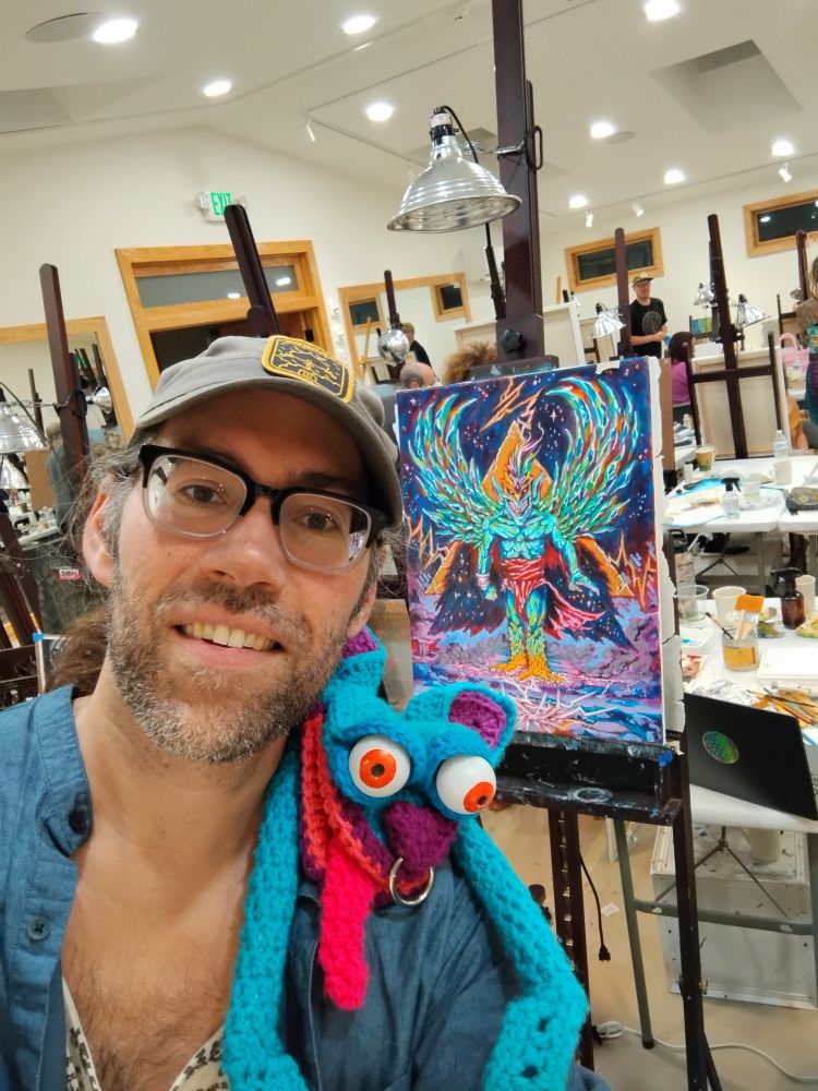Me with my puppet Gideon on my shoulder. We're standing in front of a painting I worked on at a painting workshop at Chapel of Sacred Mirrors.
