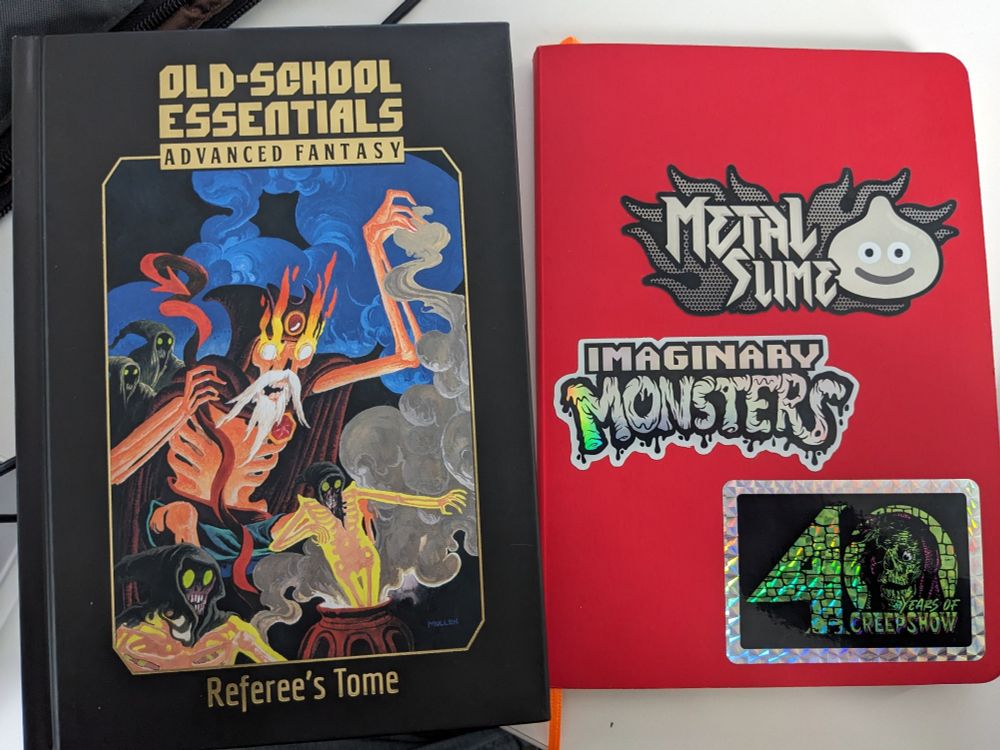 Old School Essentials Referee's Tome and my red sketchbook with dungeon maps and notes within.
