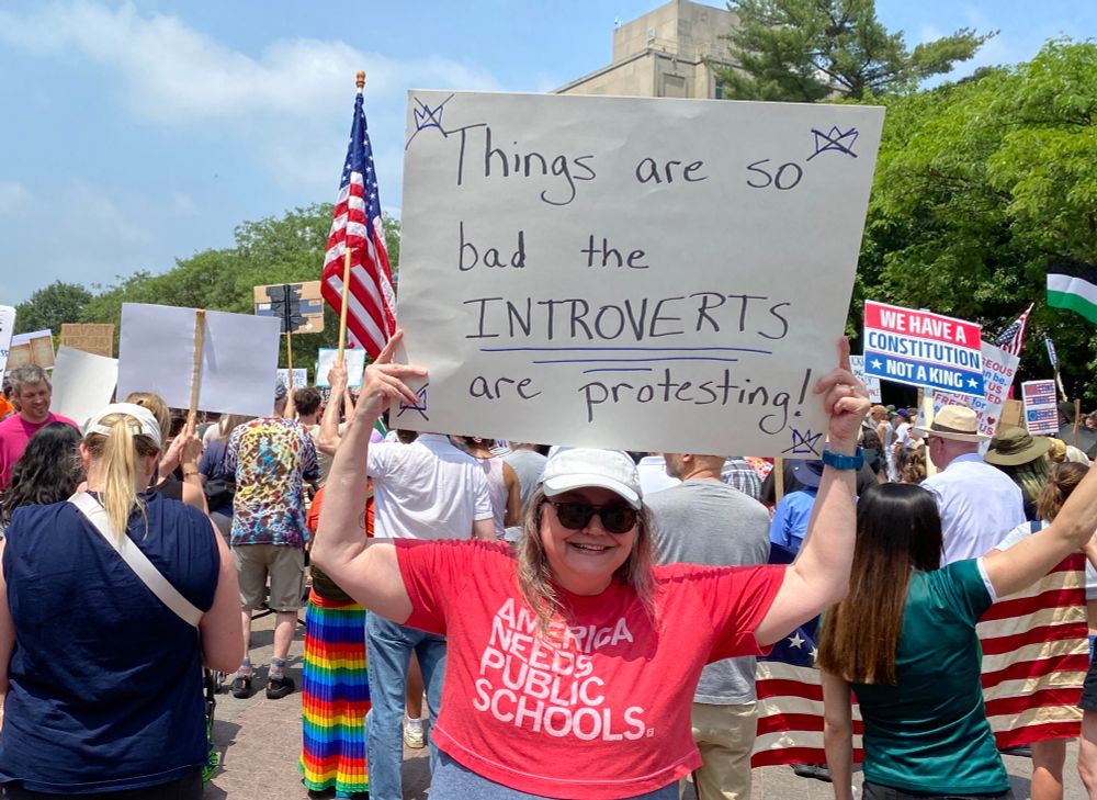 Woman at a protest. Her sign reads, “Things are so bad the INTROVERTS are protesting”