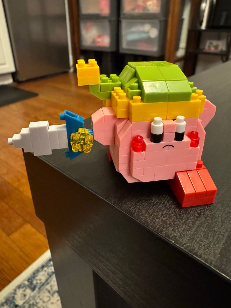 A completed sword Kirby nanoblock! Kirby is pictured with a sword and his signature green and yellow hat.
