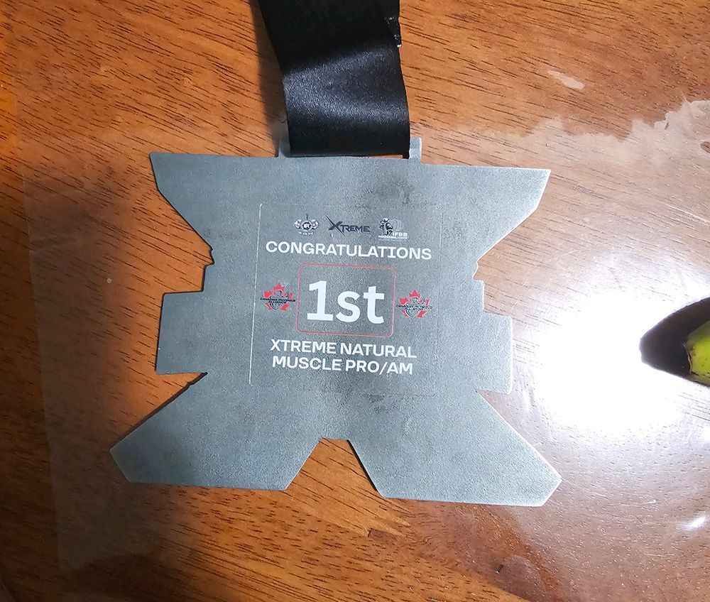 The back of the medal. It says, "Congratulations 1st Xtreme Natural Muscle Pro/Am